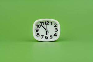 White alarm clock tells time working with time importance of time punctuality White clock on a green background photo