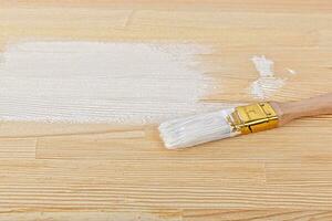 white paint with a brush on a wooden background with texture photo
