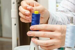 Adjusting the sewing machine, threads in female hands photo