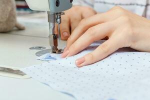 Female hands of a master tailor at work, a sewing machine needle photo