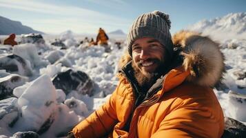 Portrait of happy man sitting on snow in winter mountains in North Pole and looking at camera. photo