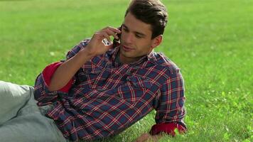 Man lying on the grass using mobile video