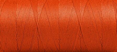 Texture of threads in a spool of Orange color on a white background photo