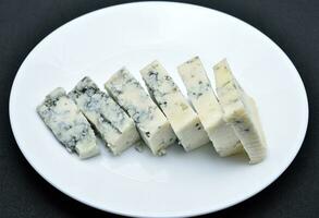 Sliced cheese with blue mold on a white plate. Delicious breakfast with cheese. photo
