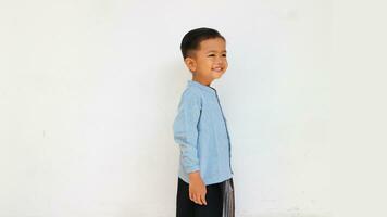 A cute and happy little boy with blue shirt and sarong looking at something photo