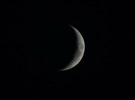 a crescent moon is seen in the dark sky photo