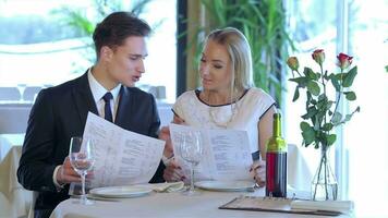 Couple thoughtfully deliberates, choosing the menu video