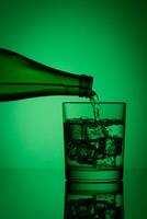 hermosa botella con agua y vaso con hielo y agua en un verde antecedentes foto