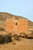 an old brick building in the middle of a desert photo