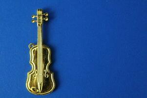 a gold plated violin charm on a blue background photo