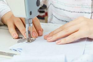 Female hands of a master tailor at work, a sewing machine needle photo