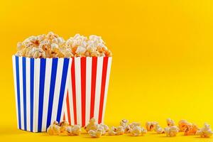 Glass with popcorn on a yellow background photo