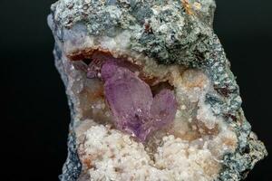 macro mineral amethyst stone in rock on a black background photo