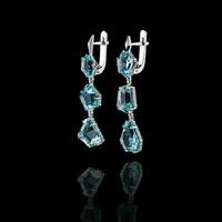 Beautiful gold earrings with aquamarine and diamonds on a black background photo