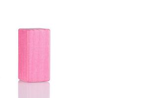 Wooden cube of pink color on a white background photo