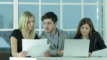 Smiling businessman sitting at the table and typing a business plan on a laptop video