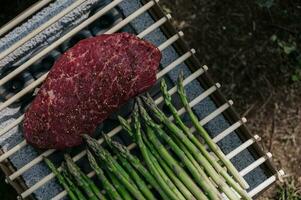 Top view on steak and asparagus preparing on grill. Summer leisure photo
