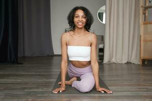 Smiling Black Woman practicing yoga at home.Wellness concept banner with place for text. photo