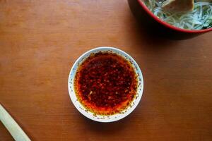 chilli oil. Homemade chilli oil in a glass liite plate, on table photo