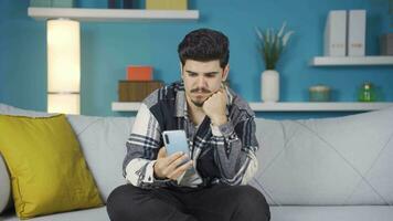 joven hombre mirando a el teléfono en desesperación y aburrimiento. video