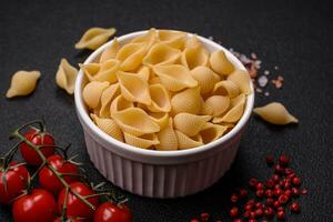 Raw Italian pasta conchiglie from durum wheat with vegetables, salt and spices photo