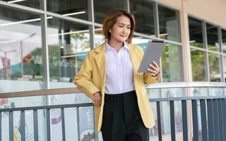 Businesswoman wearing suit and holding digital tablet video call with customer for planning management company. photo