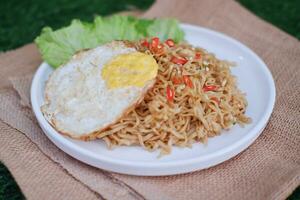 indonesian spicy noodles with egg on white plate. stock photo