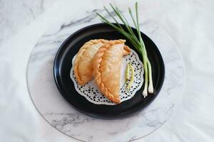 Curry puff or Pastel Goreng is Pastry Popular in Indonesia.fried pastry with filling of sauted vegetable , chicken and boiled egg. accompanied with  sauce or raw chilli pepper photo