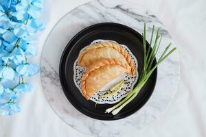 Curry puff or Pastel Goreng is Pastry Popular in Indonesia.fried pastry with filling of sauted vegetable , chicken and boiled egg. accompanied with  sauce or raw chilli pepper photo