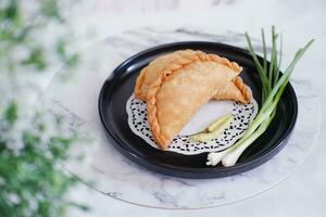 Curry puff or Pastel Goreng is Pastry Popular in Indonesia.fried pastry with filling of sauted vegetable , chicken and boiled egg. accompanied with  sauce or raw chilli pepper photo
