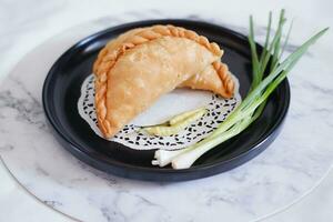 Curry puff or Pastel Goreng is Pastry Popular in Indonesia.fried pastry with filling of sauted vegetable , chicken and boiled egg. accompanied with  sauce or raw chilli pepper photo