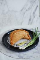 Curry puff or Pastel Goreng is Pastry Popular in Indonesia.fried pastry with filling of sauted vegetable , chicken and boiled egg. accompanied with  sauce or raw chilli pepper photo