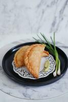 Curry puff or Pastel Goreng is Pastry Popular in Indonesia.fried pastry with filling of sauted vegetable , chicken and boiled egg. accompanied with  sauce or raw chilli pepper photo