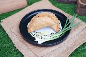 Curry puff or Pastel Goreng is Pastry Popular in Indonesia.fried pastry with filling of sauted vegetable , chicken and boiled egg. accompanied with  sauce or raw chilli pepper photo