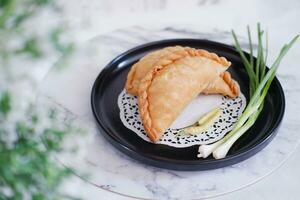 Curry puff or Pastel Goreng is Pastry Popular in Indonesia.fried pastry with filling of sauted vegetable , chicken and boiled egg. accompanied with  sauce or raw chilli pepper photo