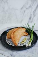 Curry puff or Pastel Goreng is Pastry Popular in Indonesia.fried pastry with filling of sauted vegetable , chicken and boiled egg. accompanied with  sauce or raw chilli pepper photo
