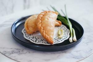 Curry puff or Pastel Goreng is Pastry Popular in Indonesia.fried pastry with filling of sauted vegetable , chicken and boiled egg. accompanied with  sauce or raw chilli pepper photo