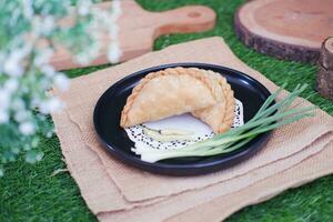 Curry puff or Pastel Goreng is Pastry Popular in Indonesia.fried pastry with filling of sauted vegetable , chicken and boiled egg. accompanied with  sauce or raw chilli pepper photo