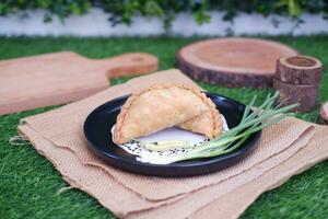 Curry puff or Pastel Goreng is Pastry Popular in Indonesia.fried pastry with filling of sauted vegetable , chicken and boiled egg. accompanied with  sauce or raw chilli pepper photo