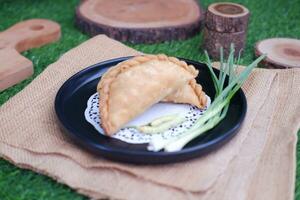 Curry puff or Pastel Goreng is Pastry Popular in Indonesia.fried pastry with filling of sauted vegetable , chicken and boiled egg. accompanied with  sauce or raw chilli pepper photo