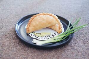 Curry puff or Pastel Goreng is Pastry Popular in Indonesia.fried pastry with filling of sauted vegetable , chicken and boiled egg. accompanied with  sauce or raw chilli pepper photo