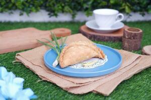 Curry puff or Pastel Goreng is Pastry Popular in Indonesia.fried pastry with filling of sauted vegetable , chicken and boiled egg. accompanied with  sauce or raw chilli pepper photo