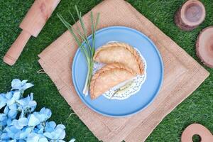 Curry puff or Pastel Goreng is Pastry Popular in Indonesia.fried pastry with filling of sauted vegetable , chicken and boiled egg. accompanied with  sauce or raw chilli pepper photo