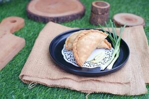 Curry puff or Pastel Goreng is Pastry Popular in Indonesia.fried pastry with filling of sauted vegetable , chicken and boiled egg. accompanied with  sauce or raw chilli pepper photo