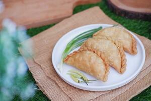 Curry puff or Pastel Goreng is Pastry Popular in Indonesia. fried pastry with filling of sauted vegetable, chicken and boiled egg. accompanied with  sauce or raw chilli pepper photo
