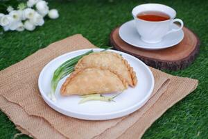 Curry puff or Pastel Goreng is Pastry Popular in Indonesia. fried pastry with filling of sauted vegetable, chicken and boiled egg. accompanied with  sauce or raw chilli pepper photo
