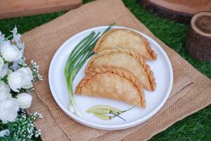 Curry puff or Pastel Goreng is Pastry Popular in Indonesia. fried pastry with filling of sauted vegetable, chicken and boiled egg. accompanied with  sauce or raw chilli pepper photo