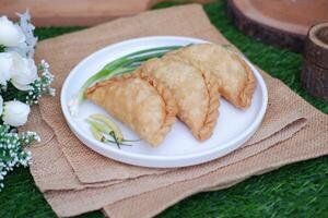 Curry puff or Pastel Goreng is Pastry Popular in Indonesia. fried pastry with filling of sauted vegetable, chicken and boiled egg. accompanied with  sauce or raw chilli pepper photo