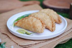 Curry puff or Pastel Goreng is Pastry Popular in Indonesia. fried pastry with filling of sauted vegetable, chicken and boiled egg. accompanied with  sauce or raw chilli pepper photo