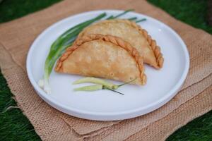 Curry puff or Pastel Goreng is Pastry Popular in Indonesia. fried pastry with filling of sauted vegetable, chicken and boiled egg. accompanied with  sauce or raw chilli pepper photo